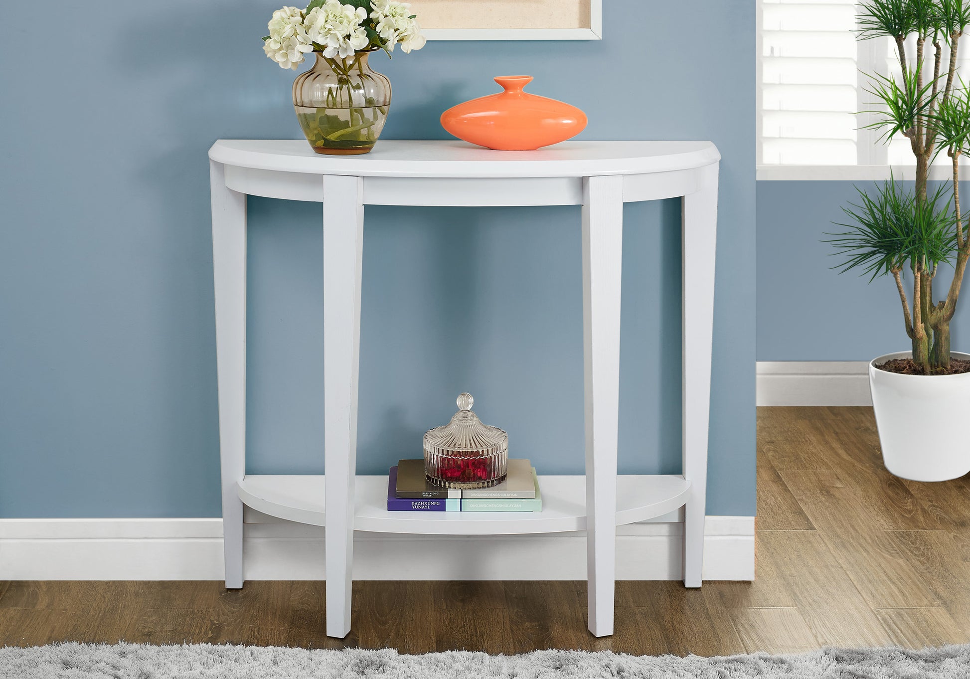 White halfmoon console table with floral arrangement and orange vase perfect for entryways