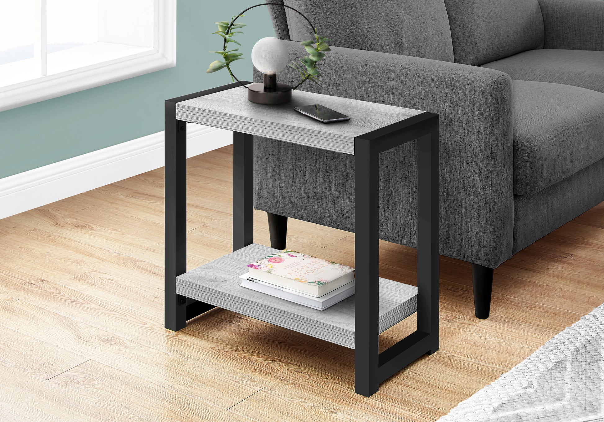 Grey wood and black metal end table with a lamp and phone on top