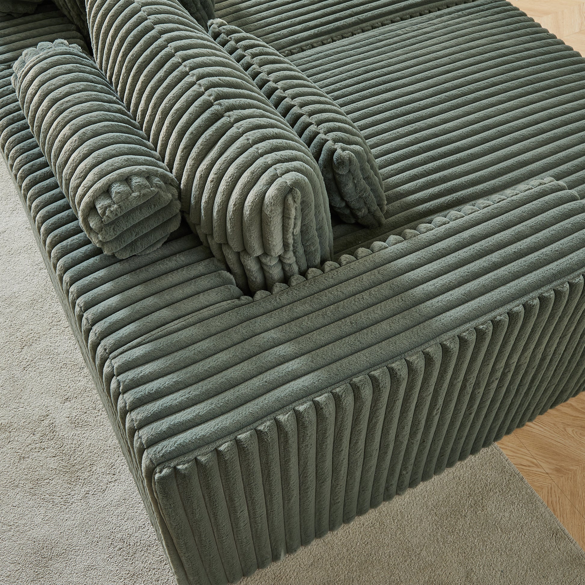 Sage green corduroy sofa with plush rounded bolsters and a deep seat cushion