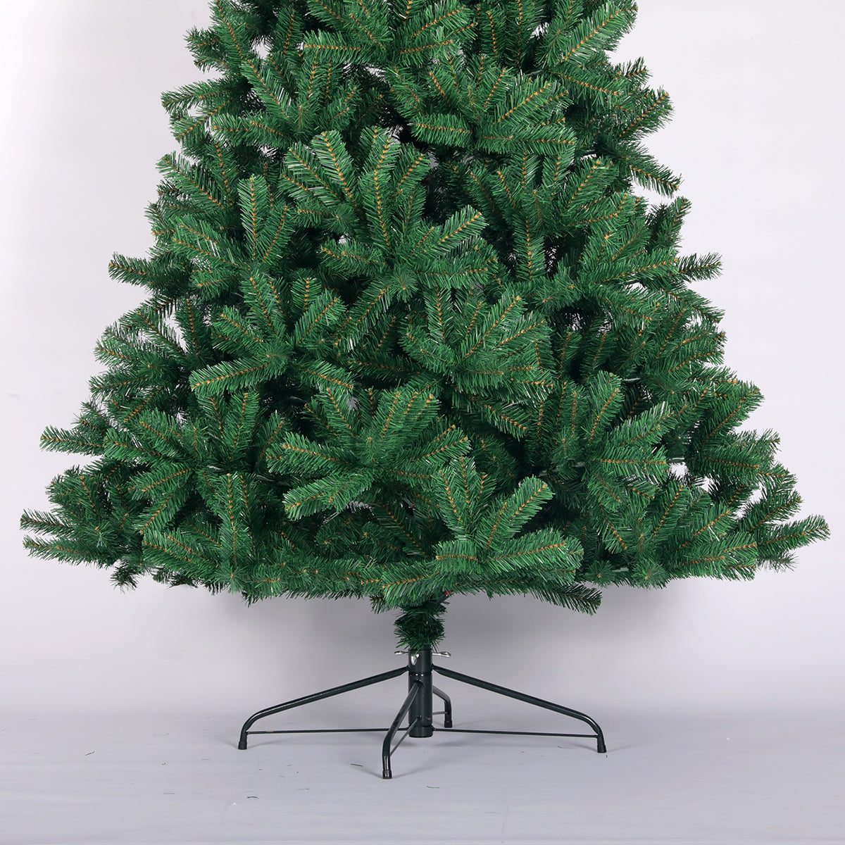 Green artificial christmas tree with realistic pine needles and metal stand