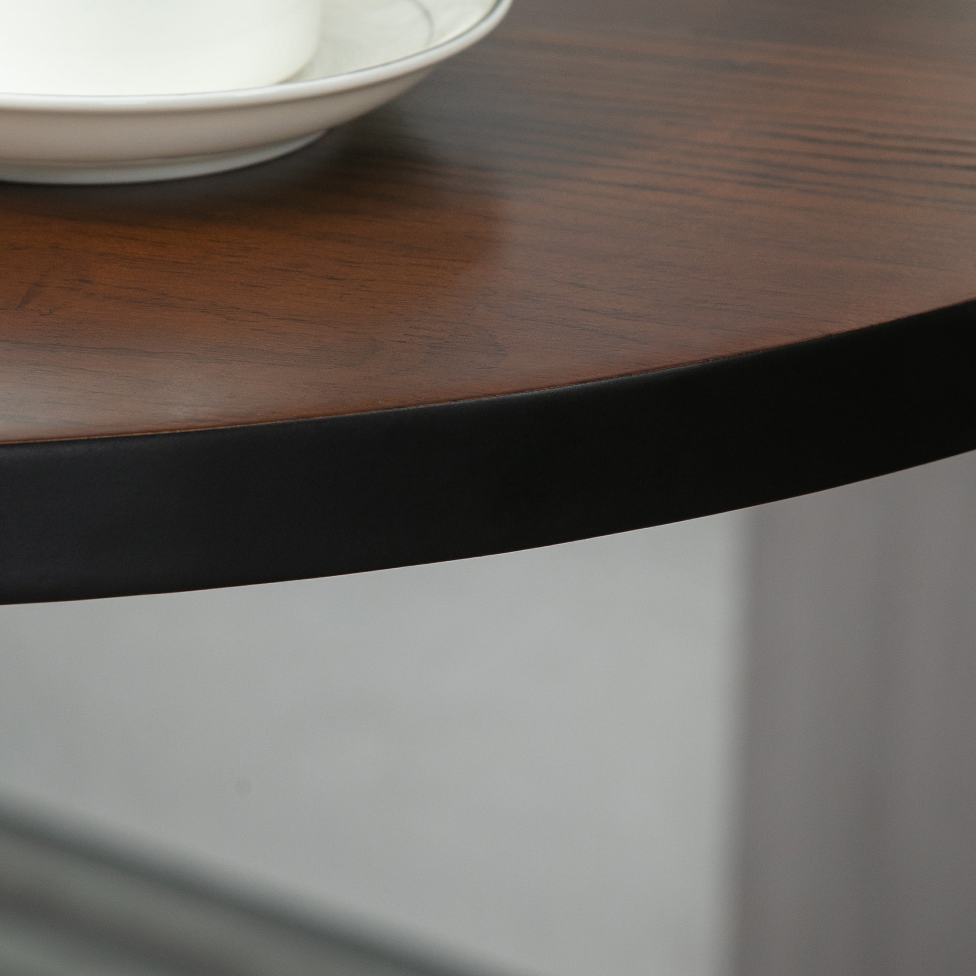 Closeup of a circular wood grain table top with a black metal edge detail