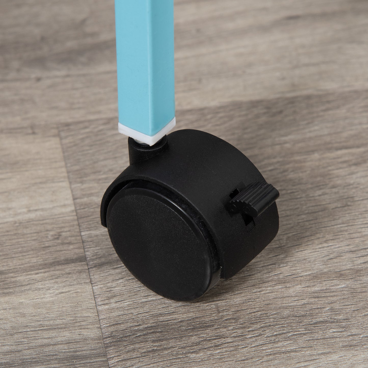 Closeup of a black locking caster wheel attached to a light blue metal leg on a woodgrain floor