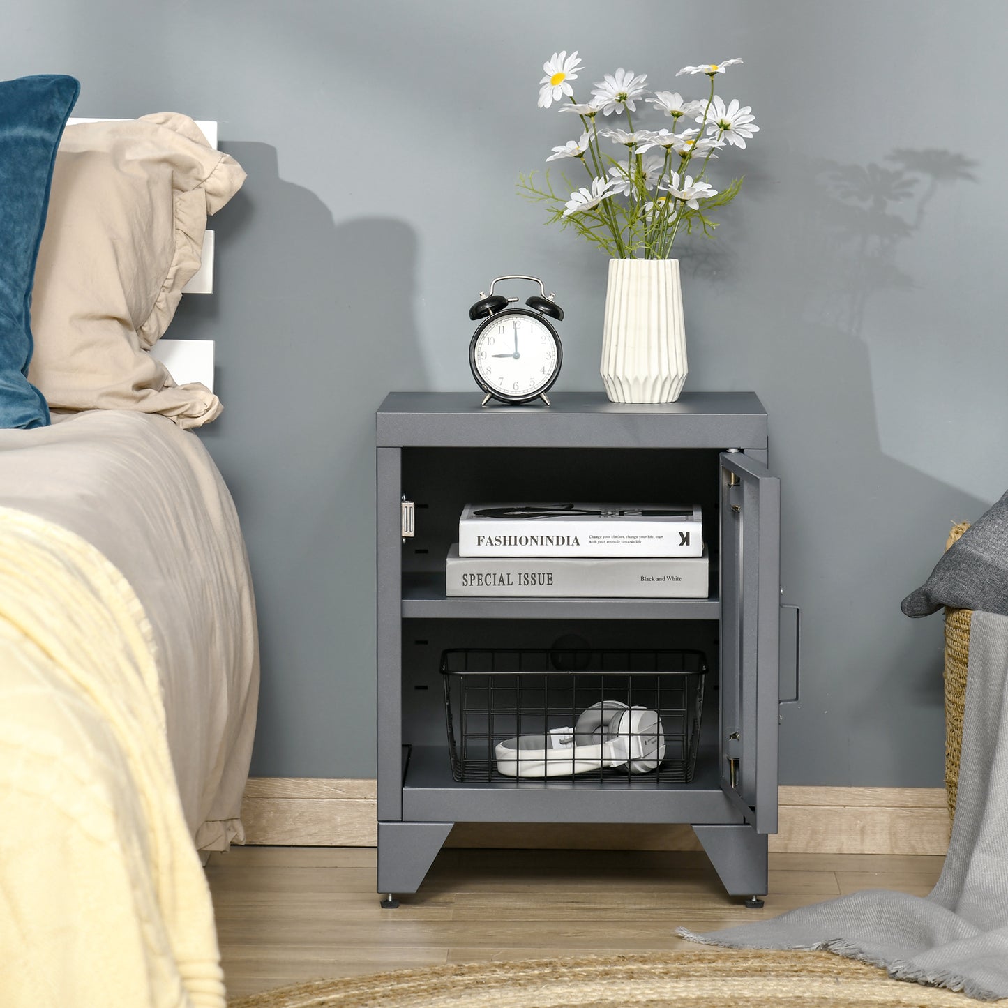 Gray metal bedside cabinet with open door holding books and basket