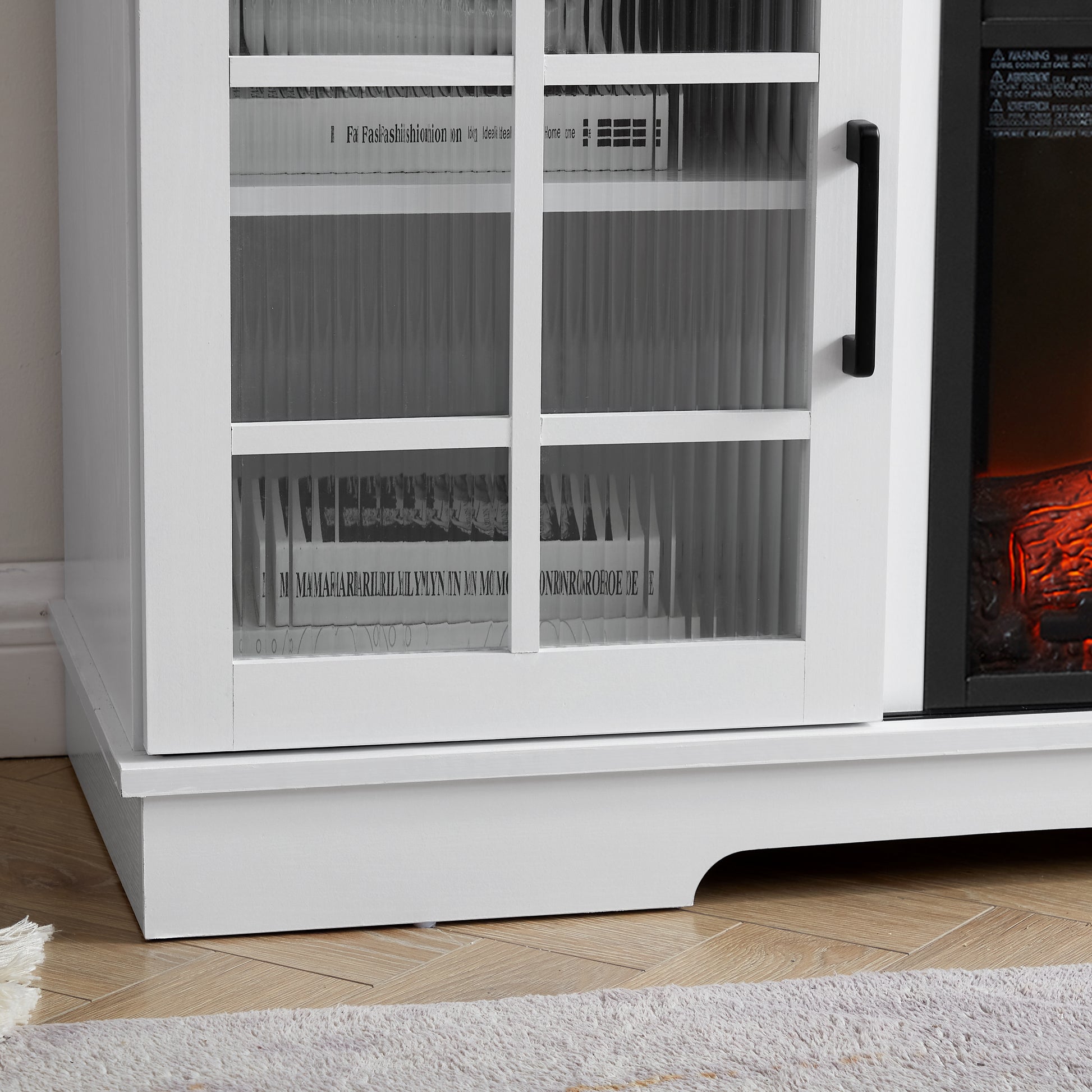 White media console with glass doors displaying decorative books and faux fireplace