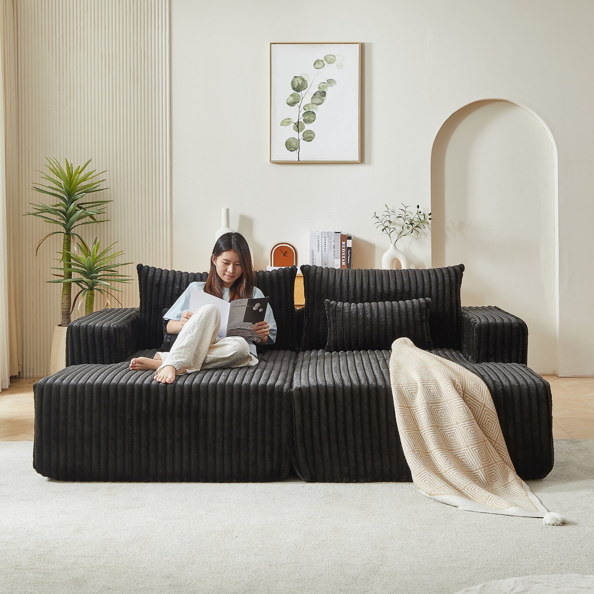 Black corduroy sectional sofa with plush throw pillows and a diamondpatterned throw blanket
