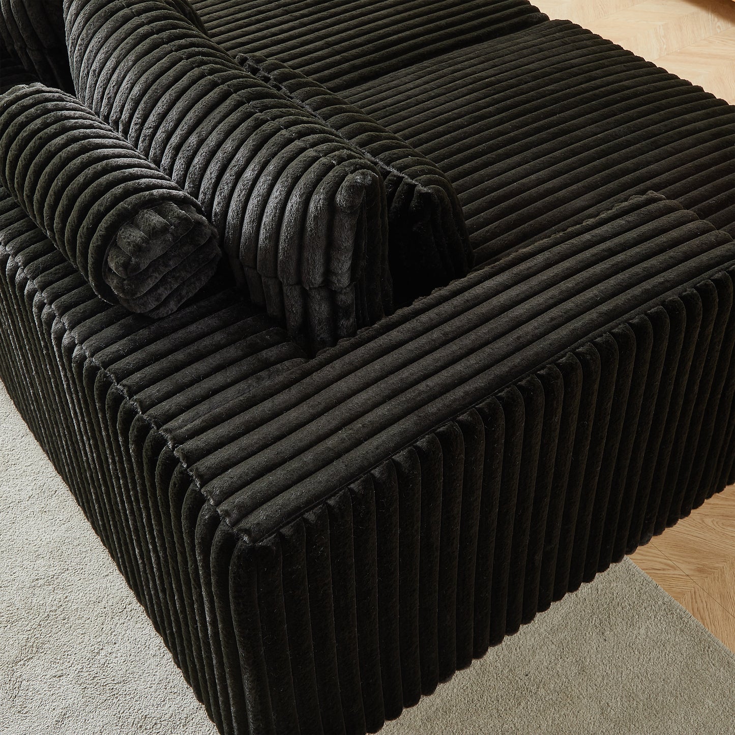 Plush black corduroy sofa section with textured channeling and plush bolster pillows