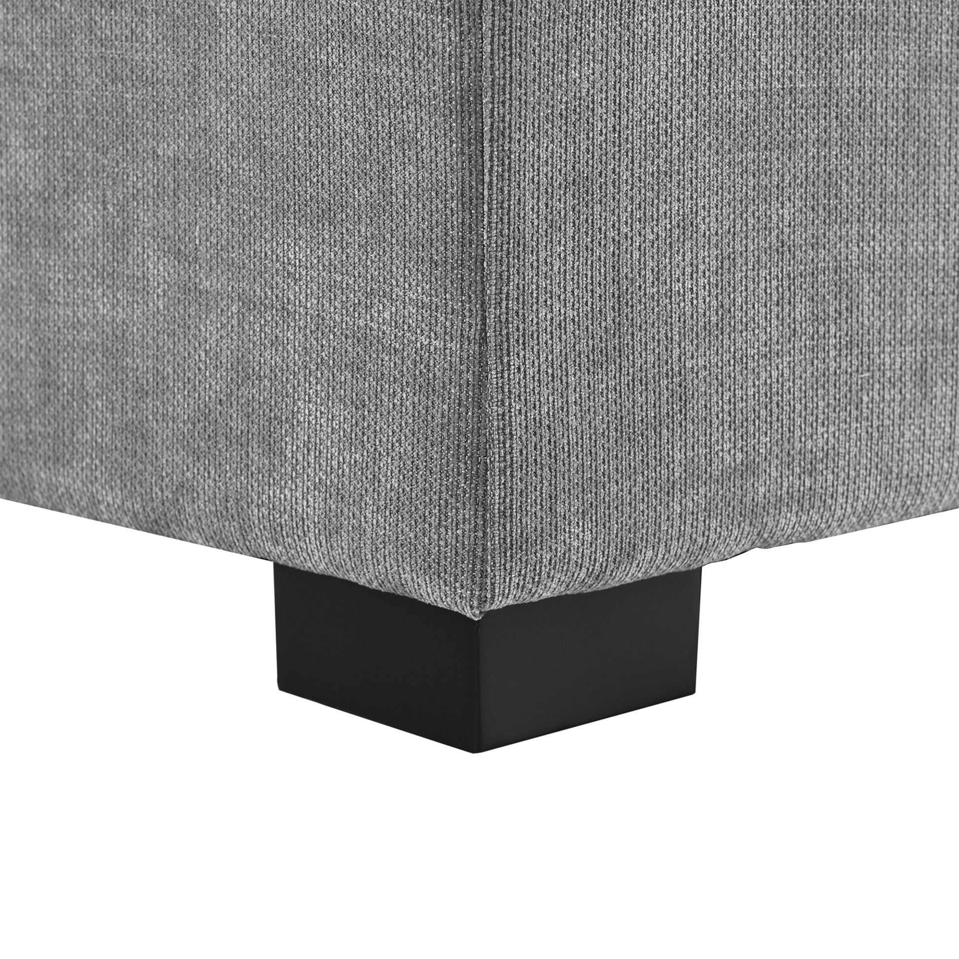Closeup of a grey textured fabric sofa corner with a black square leg