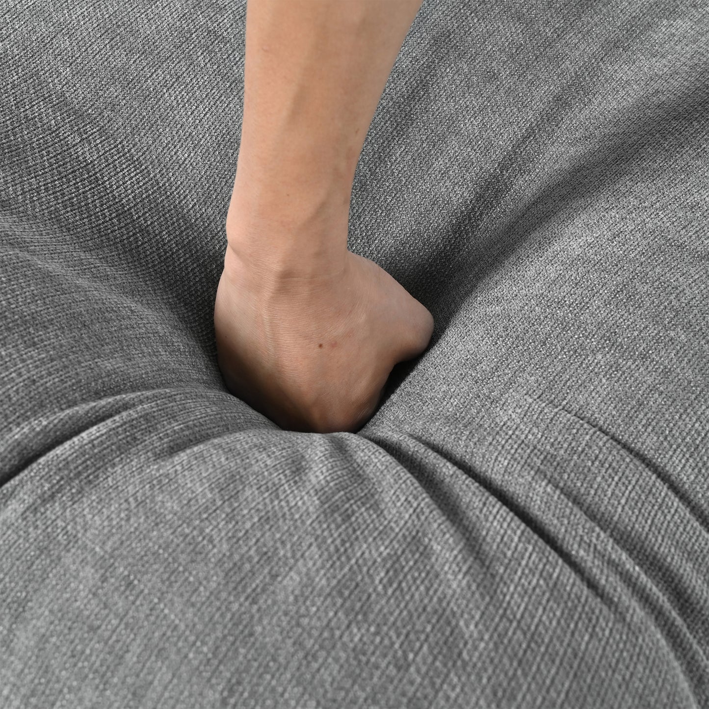 Hand pressing into soft grey textured fabric cushion