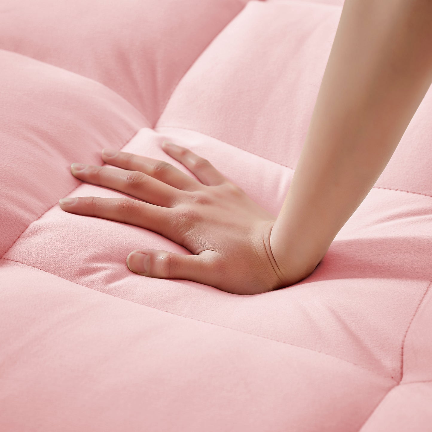 Closeup of a hand pressing into plush pink velvet sofa cushion for comfort