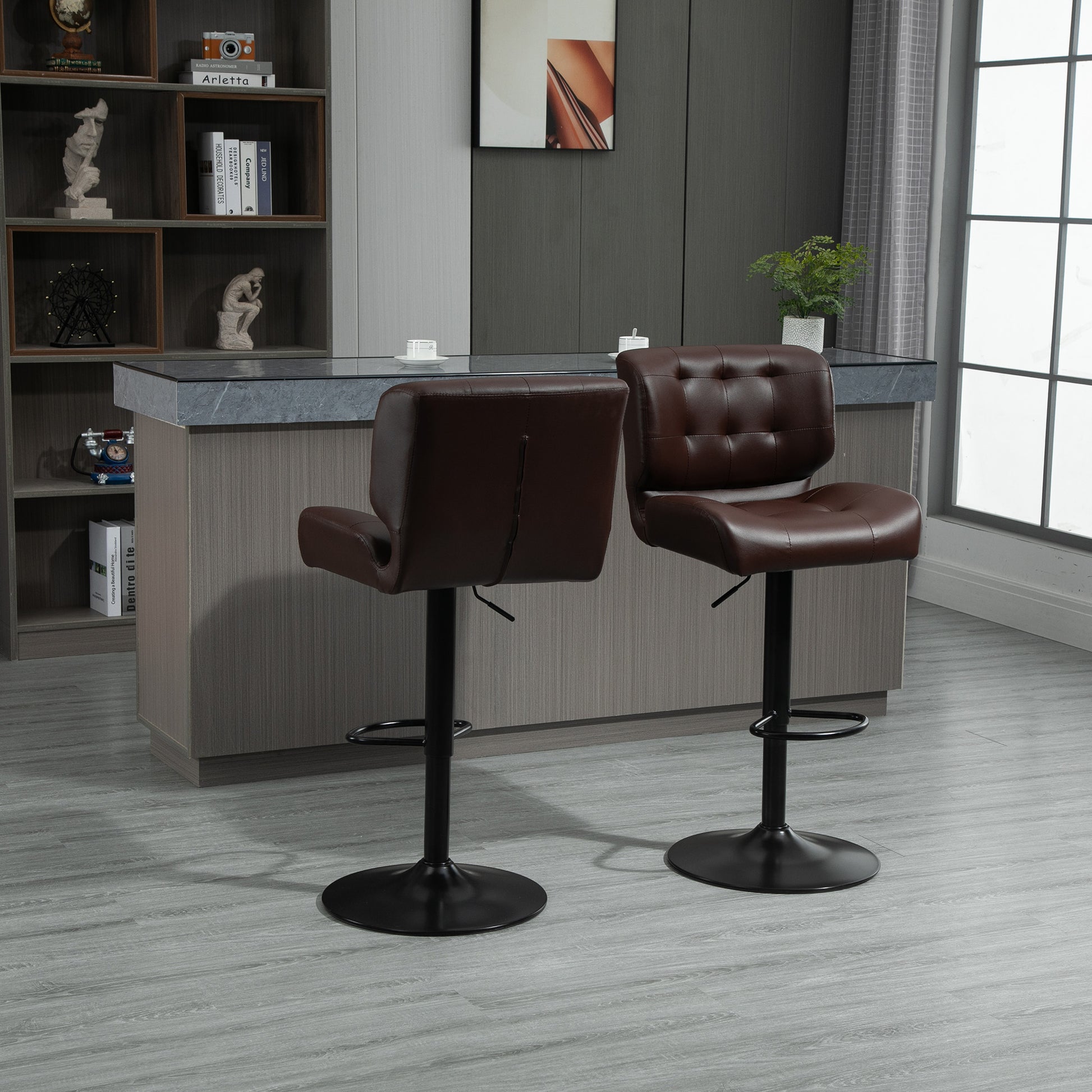 Two brown tufted leather bar stools with adjustable height and black metal bases