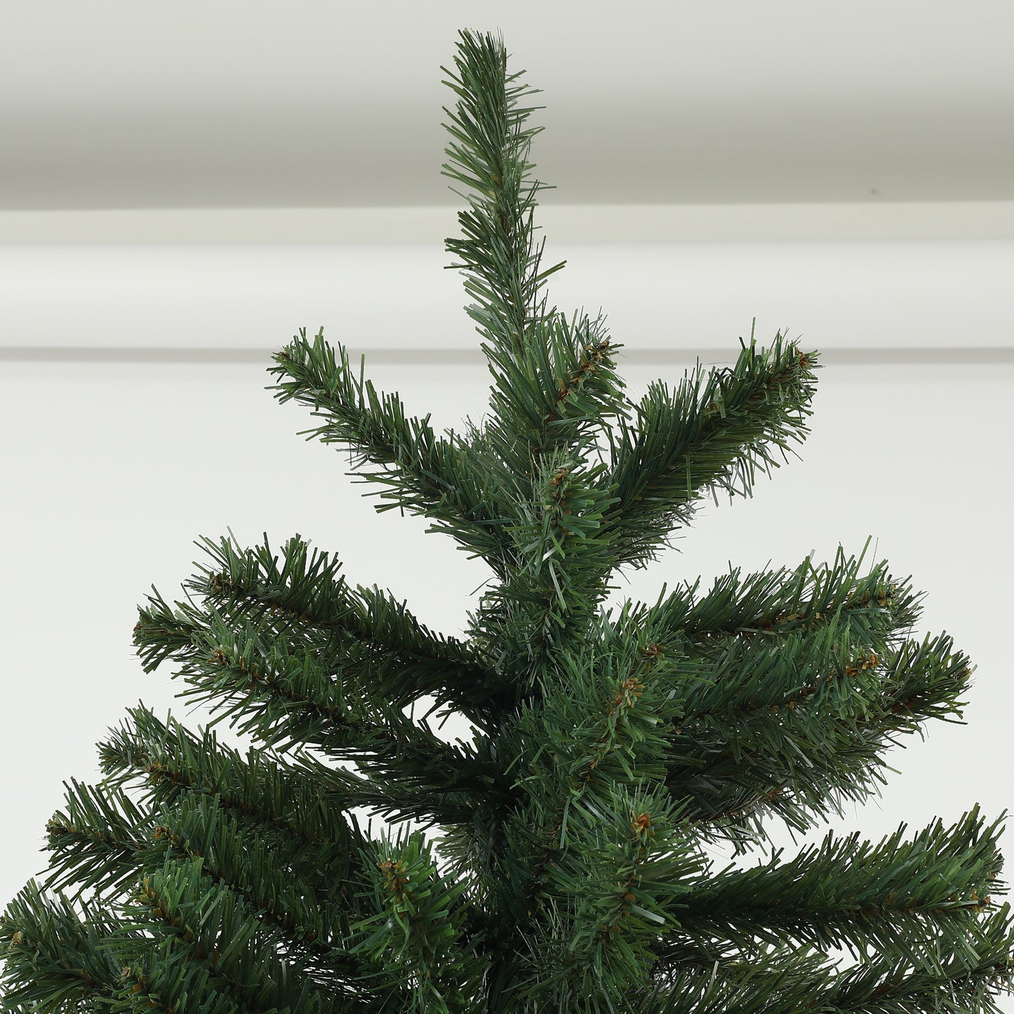Closeup of a realistic artificial christmas tree with dense green pine needles and small brown tips