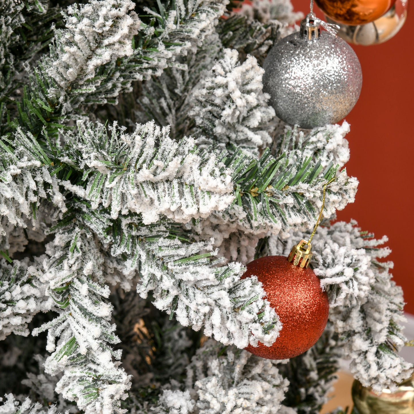 Snowdusted flocked artificial pine tree branches with red glitter ornament