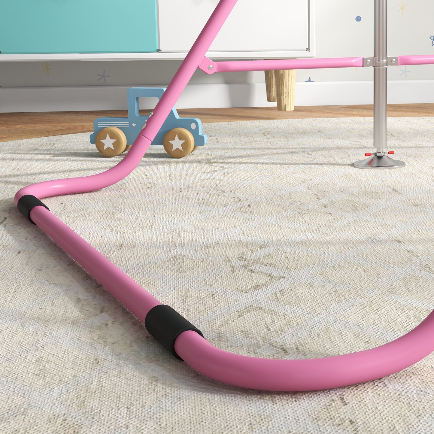 Closeup of a pink metal frame with black grip detail part of a balance bike