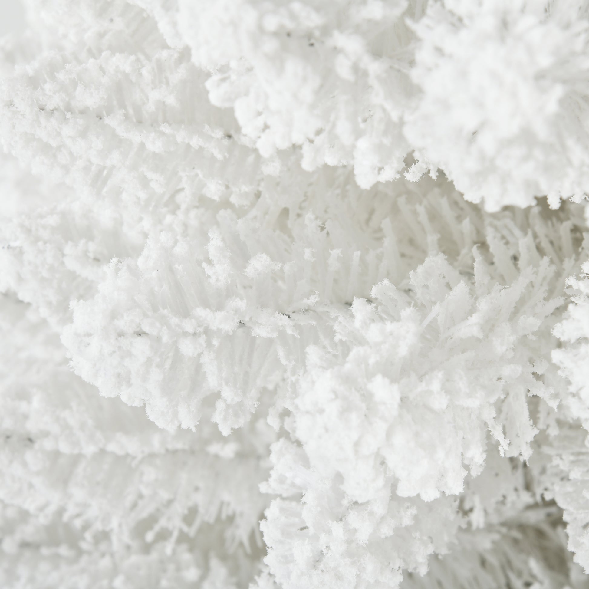 Closeup of fluffy white artificial snowcovered pine needles on a Christmas tree