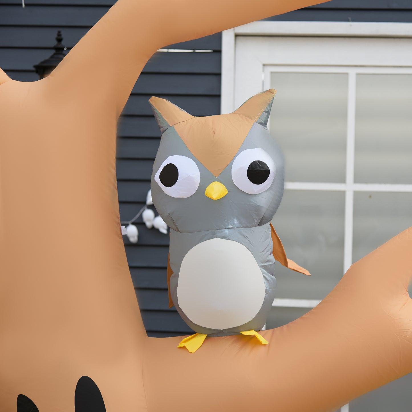 Inflatable owl decoration gray owl with large white eyes and yellow beak on brown branches
