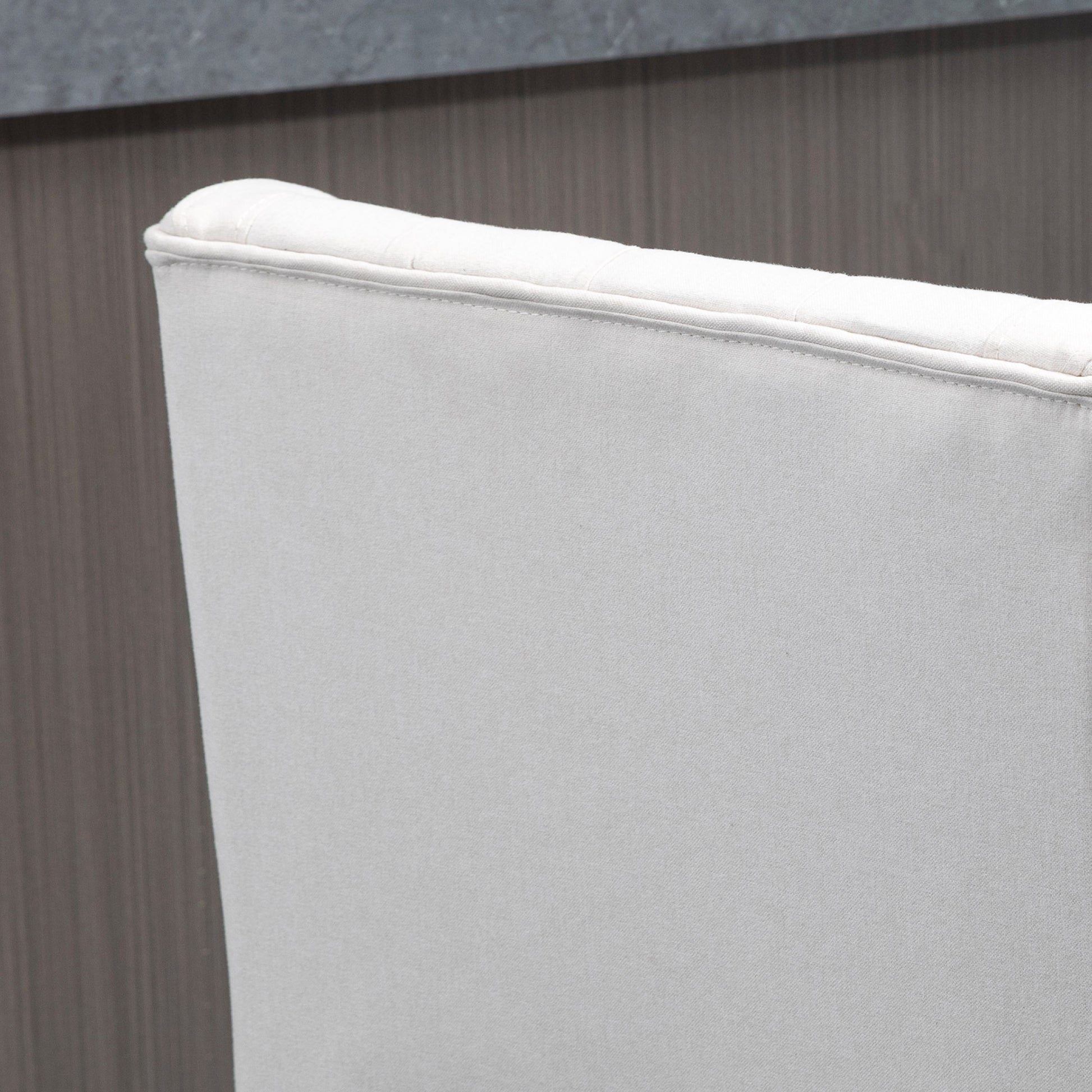 Closeup of a light gray linen chair back with subtle stitching detail