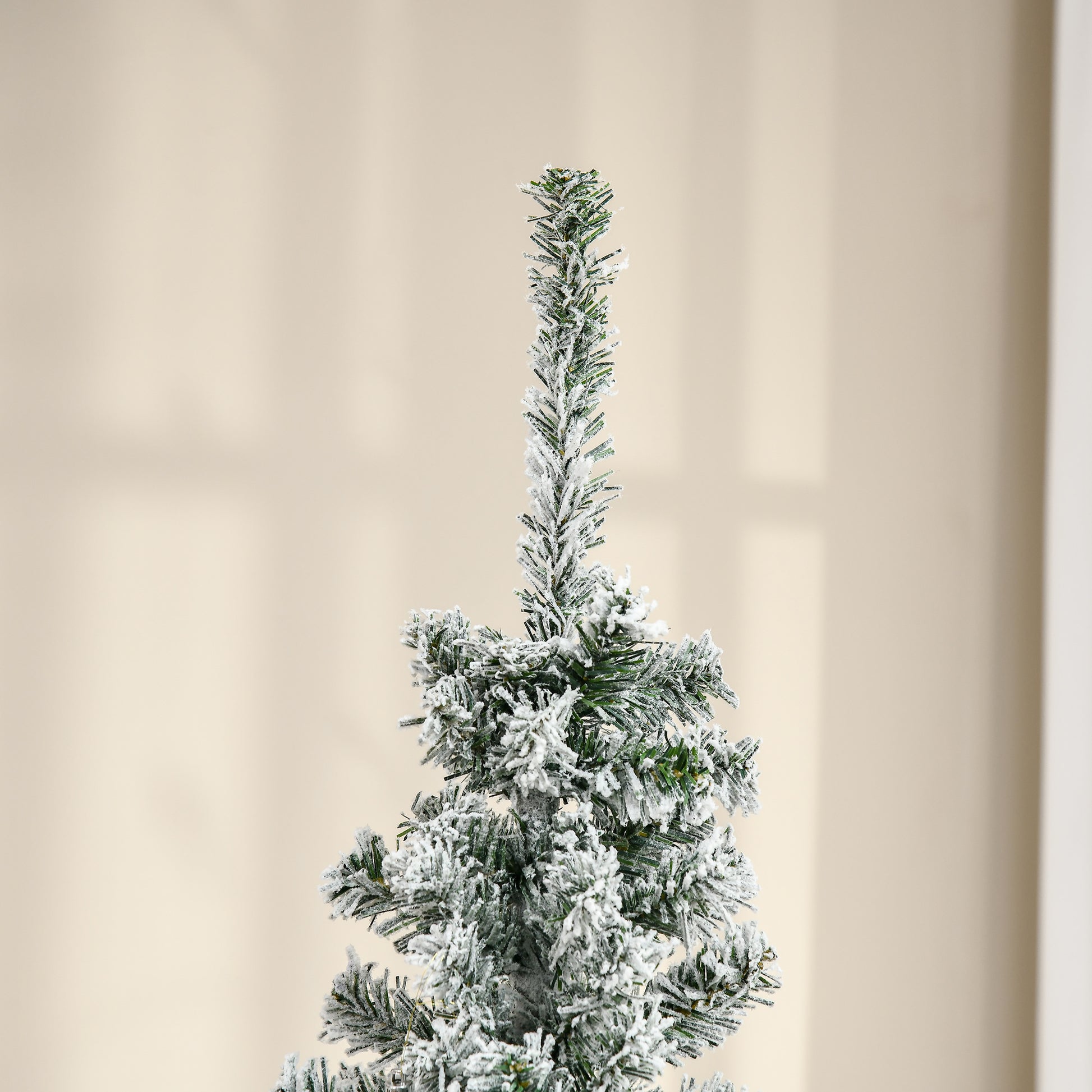 Frosted green pine branches of a flocked Christmas tree with artificial snow coating