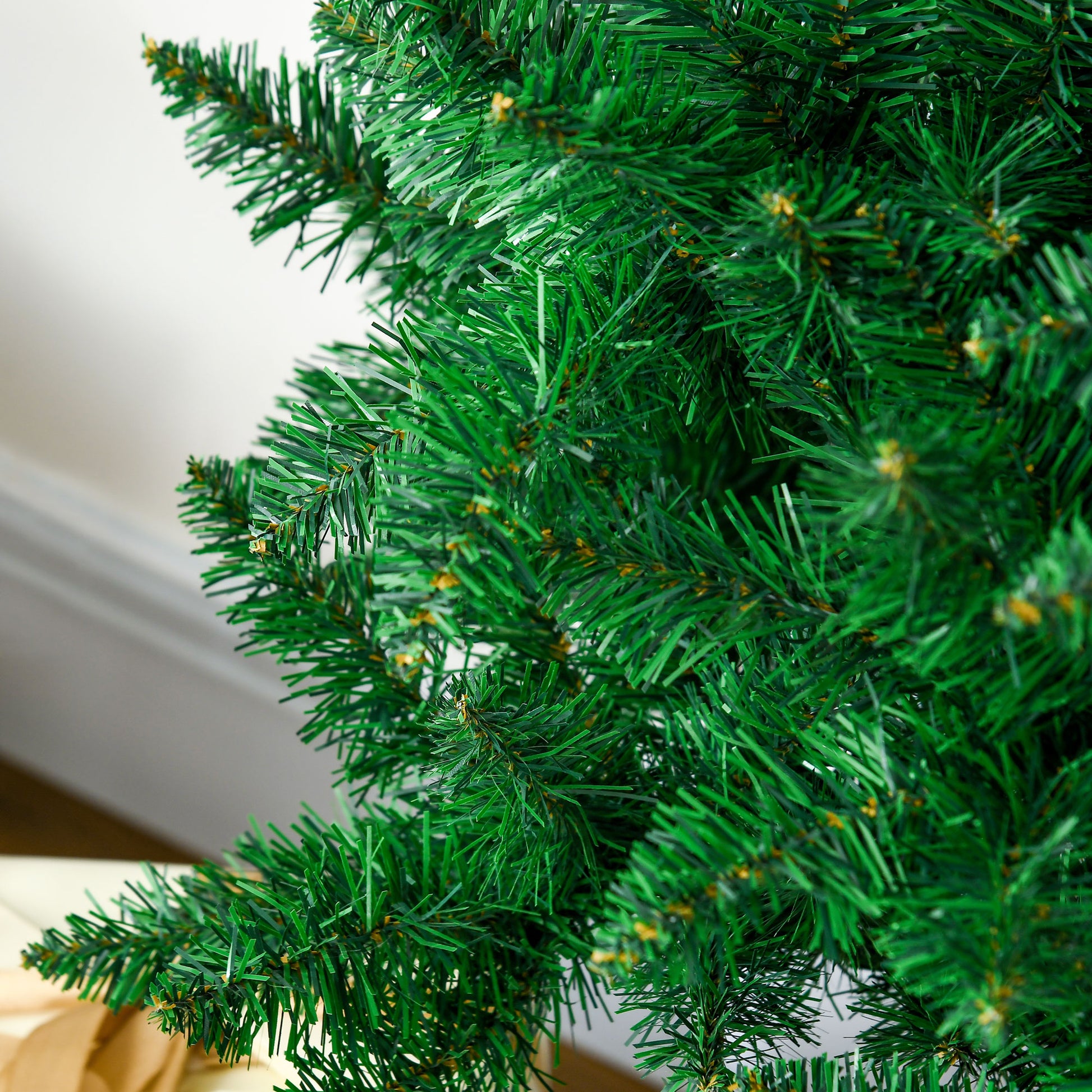 Closeup of lush green artificial Christmas tree branches with subtle gold accents
