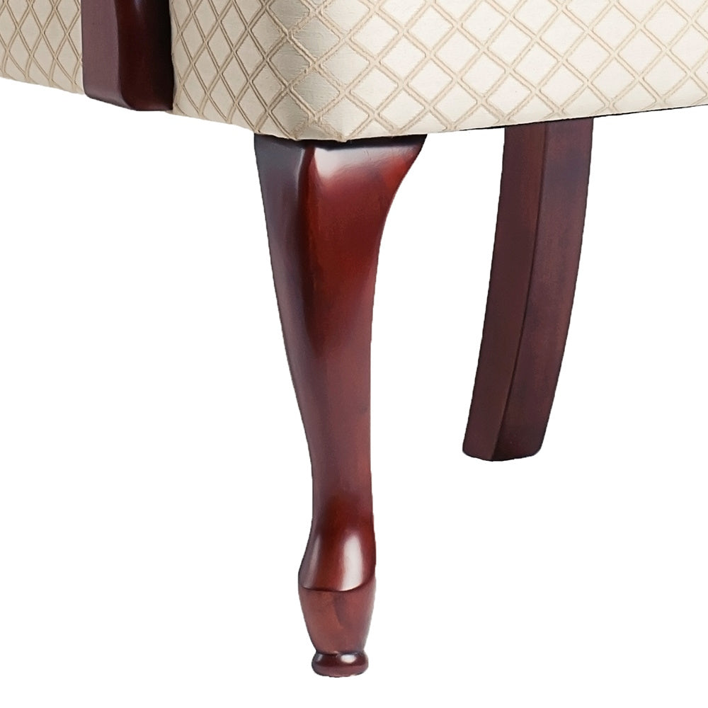 Curved dark wood cabriole leg on a diamondstitched cream armchair
