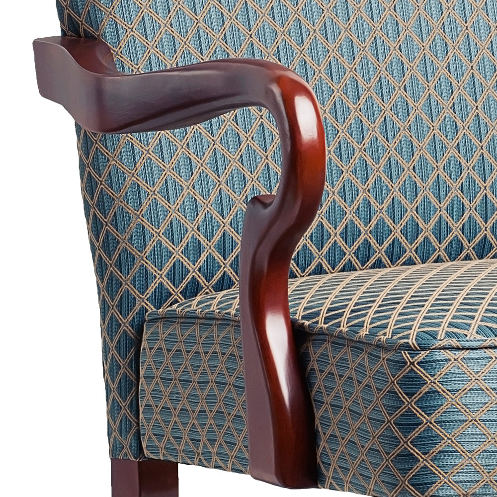 Closeup of mahogany armchair armrest with blue diamond patterned fabric