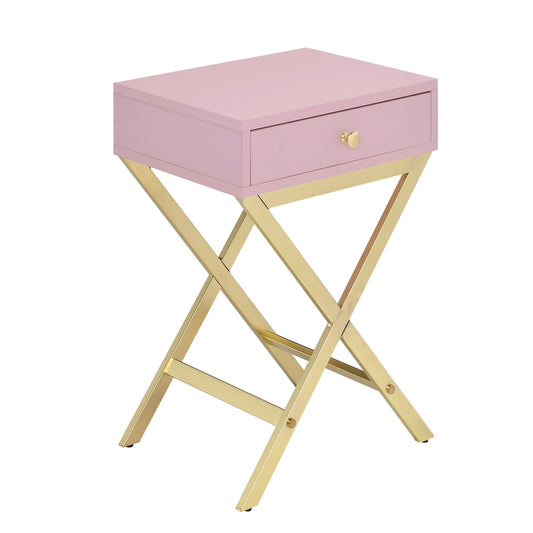 Pale pink bedside table with gold crisscross legs and single drawer with brass knob