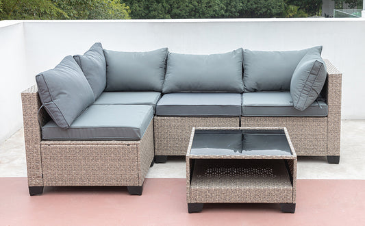 Wicker sectional patio sofa with grey cushions and a glasstop coffee table