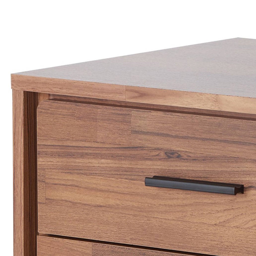 Closeup of a wooden dresser drawer with a matte black handle