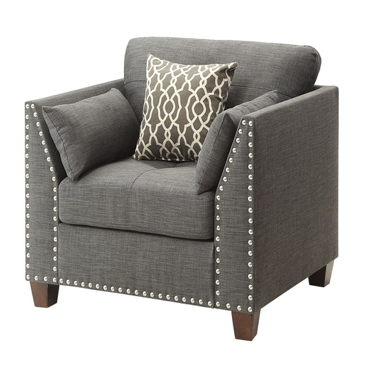 Dark gray upholstered accent chair with nailhead trim and patterned throw pillow