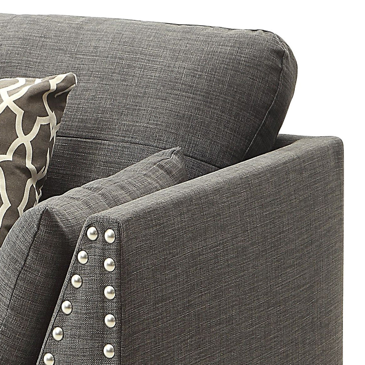 Dark gray upholstered armchair with decorative nailhead trim and patterned throw pillow
