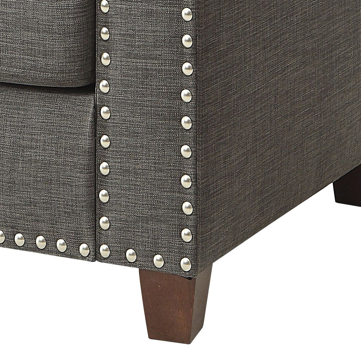 Close up of dark gray fabric sofa with decorative silver nailhead trim
