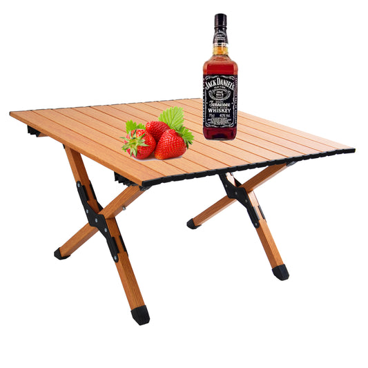 Wooden folding camping table with fresh strawberries and Jack Daniels bottle