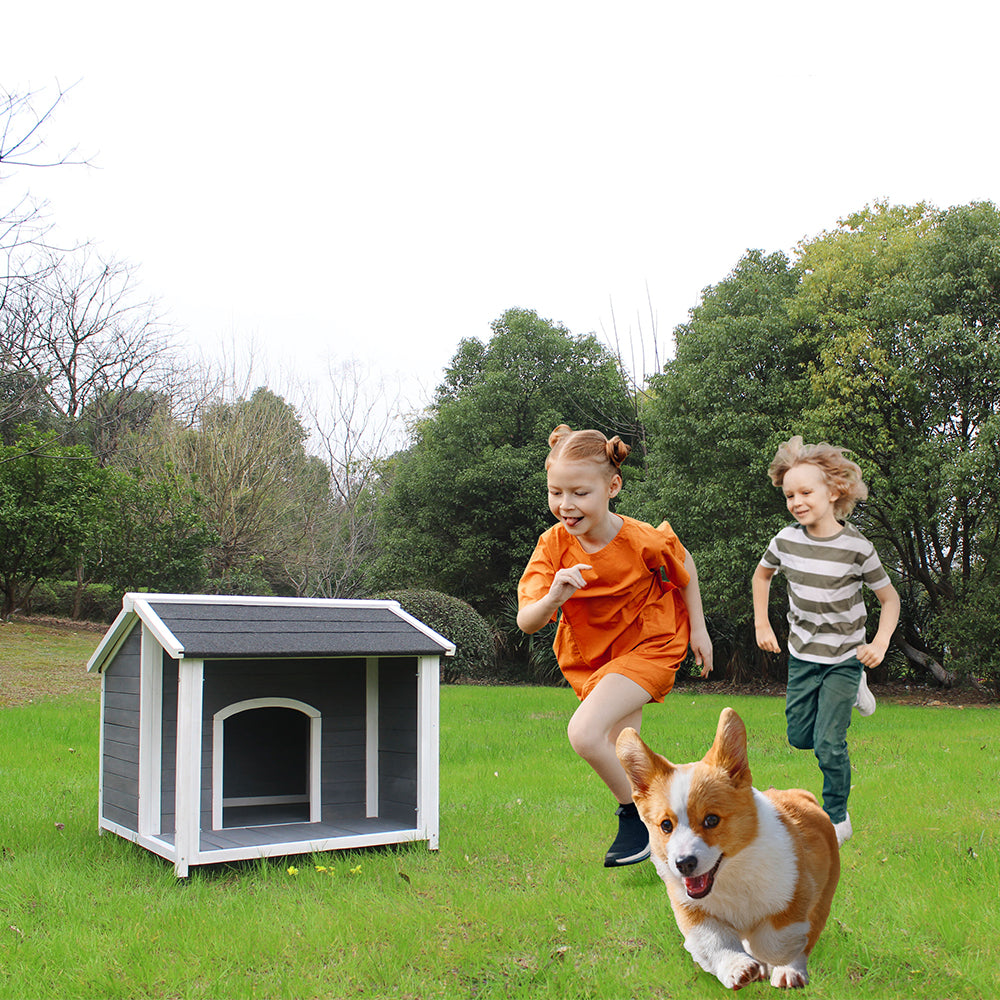 Gray wooden dog house with white trim in a grassy yard