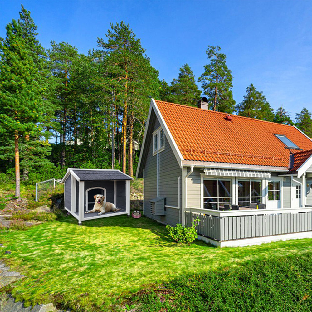 Gray wooden dog house with asphalt roof featuring a Labrador resting inside