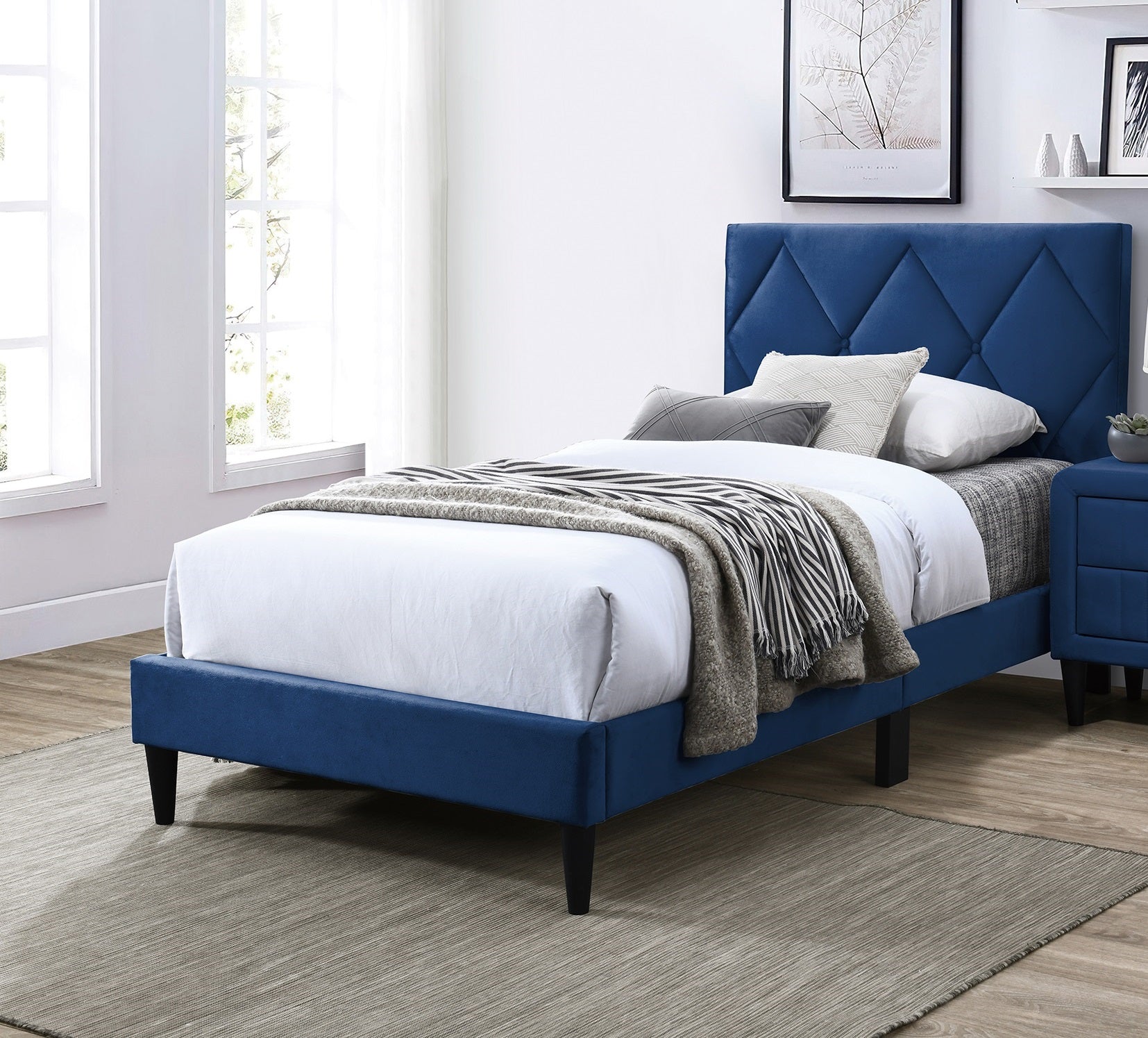 Blue upholstered bed frame with diamond tufted headboard and white linens