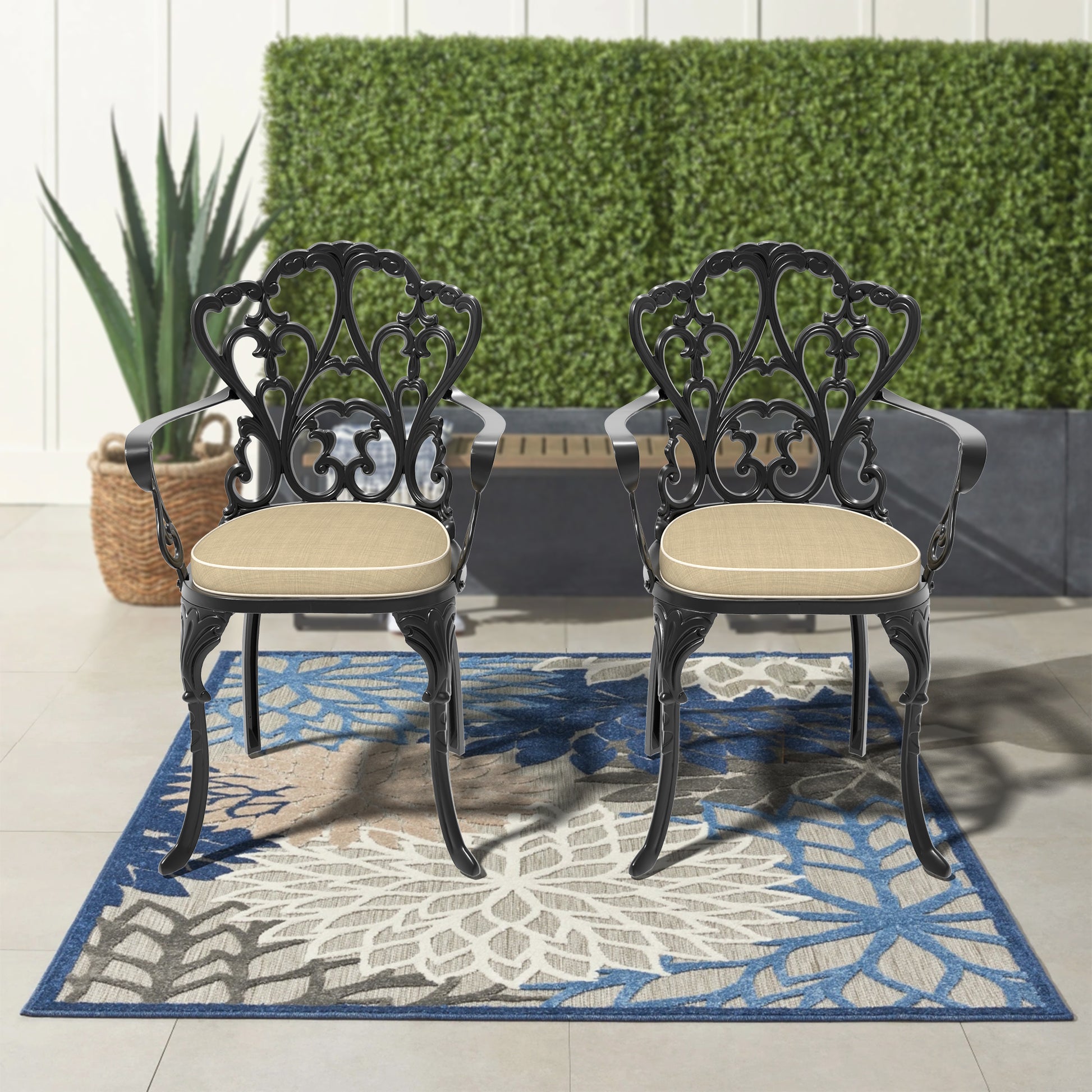 Pair of ornate black cast aluminum patio chairs with tan cushions