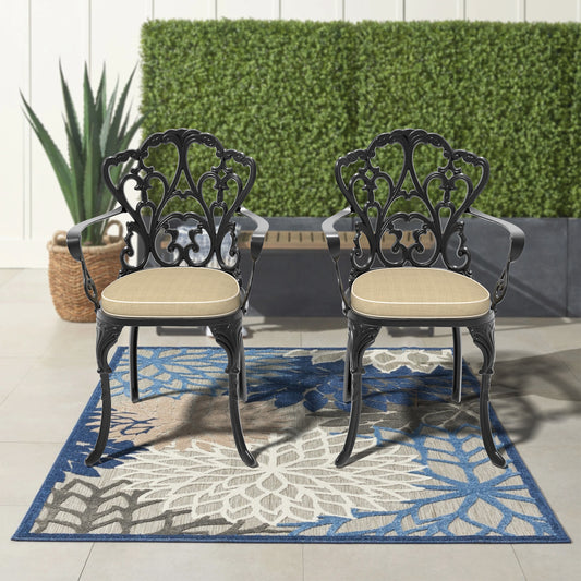 Pair of ornate black cast aluminum patio chairs with tan cushions