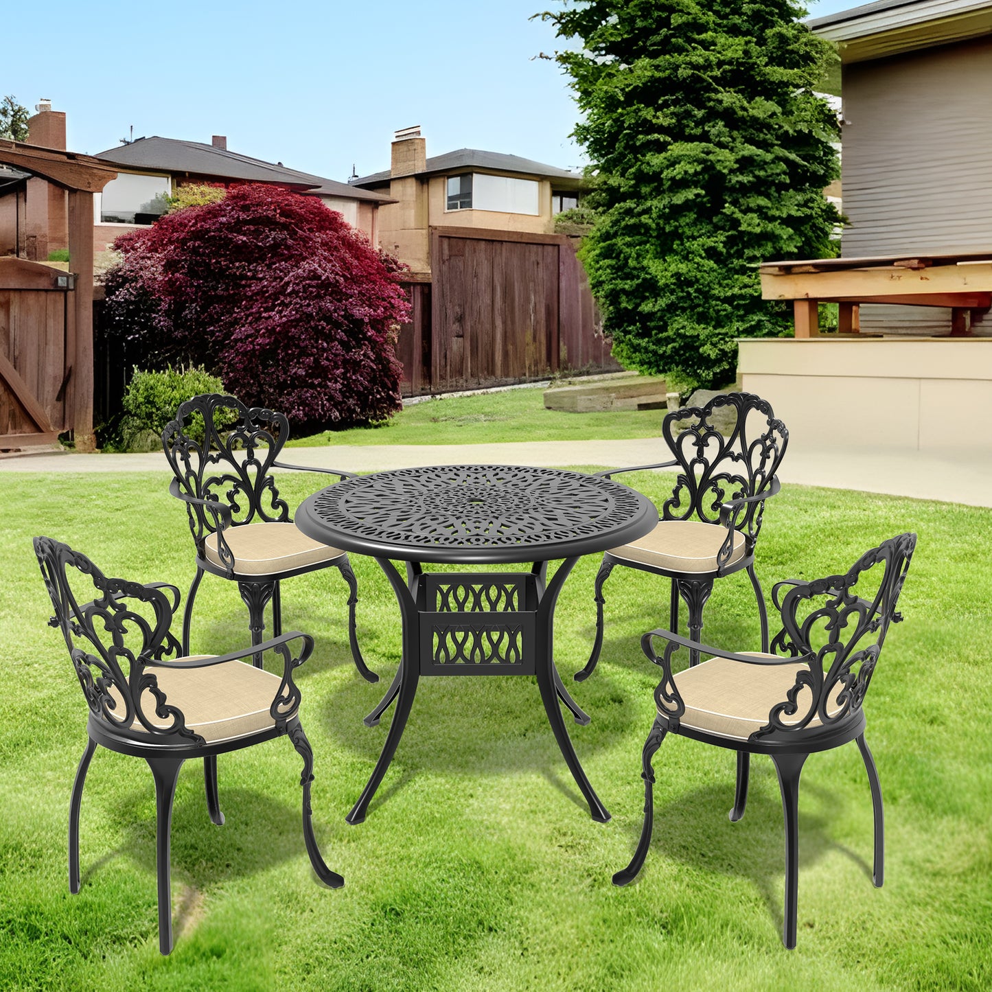 Black cast aluminum patio dining set with ornate scrollwork chairs and round table on green grass