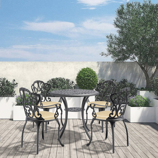Black cast iron bistro set with ornate detailing and tan cushions