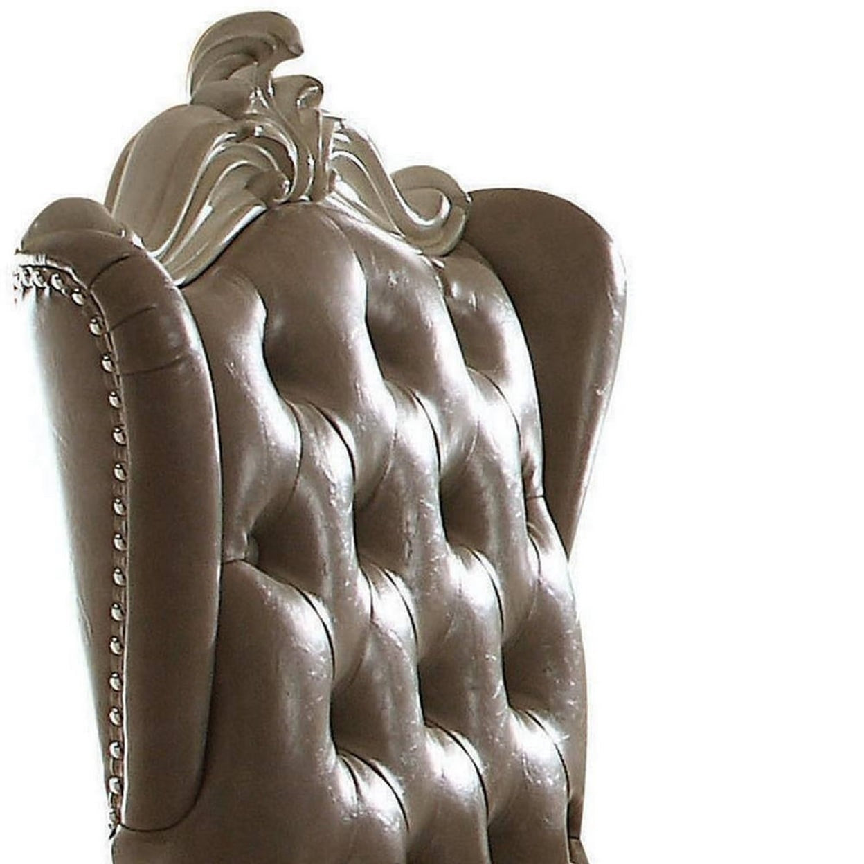 Brown tufted leather armchair with ornate top detail and nailhead trim