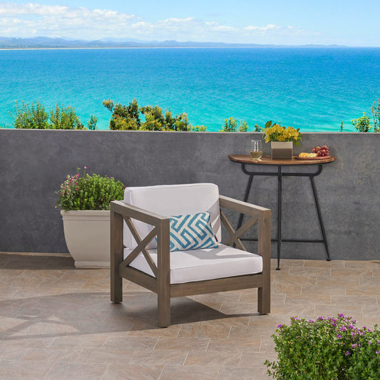 Weathered gray wood outdoor chair with white cushions and geometric pillow