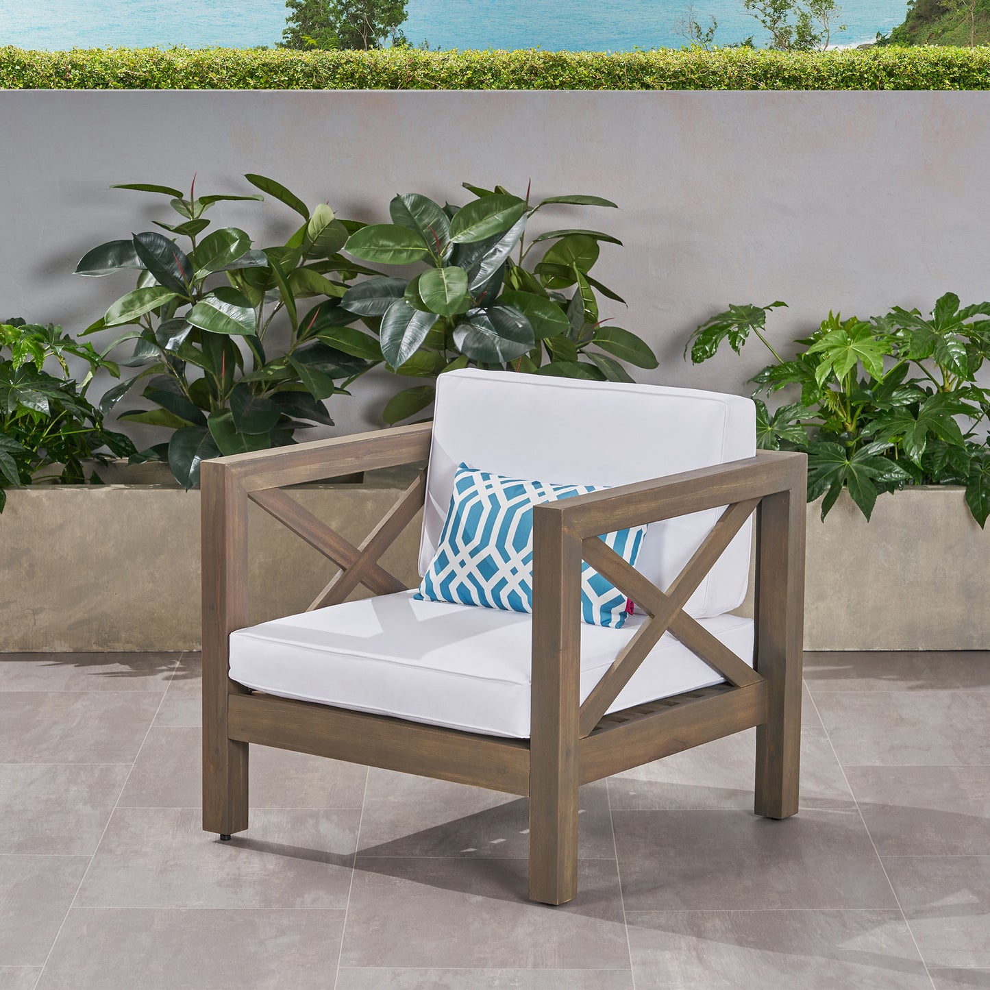 Wooden outdoor chair with white cushions and a geometric blue pillow