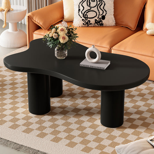 Black organic shape coffee table with thick cylindrical legs on a checkered rug