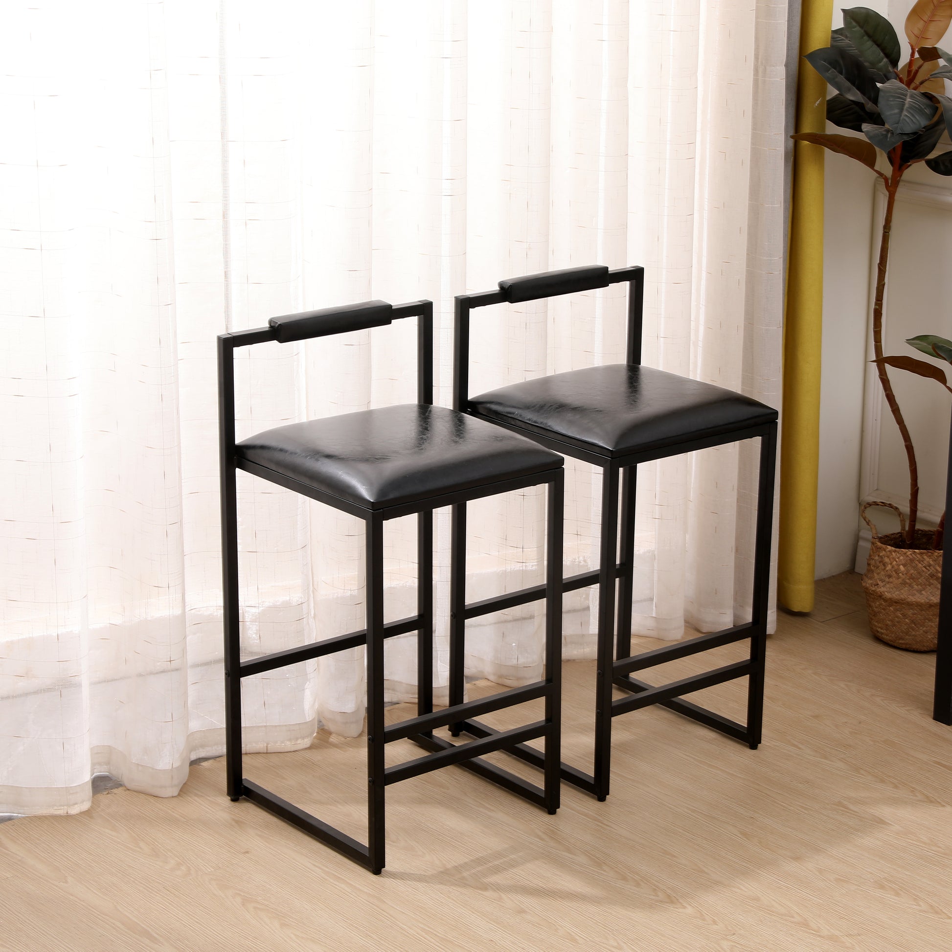 Two black faux leather bar stools with metal frames and armrests