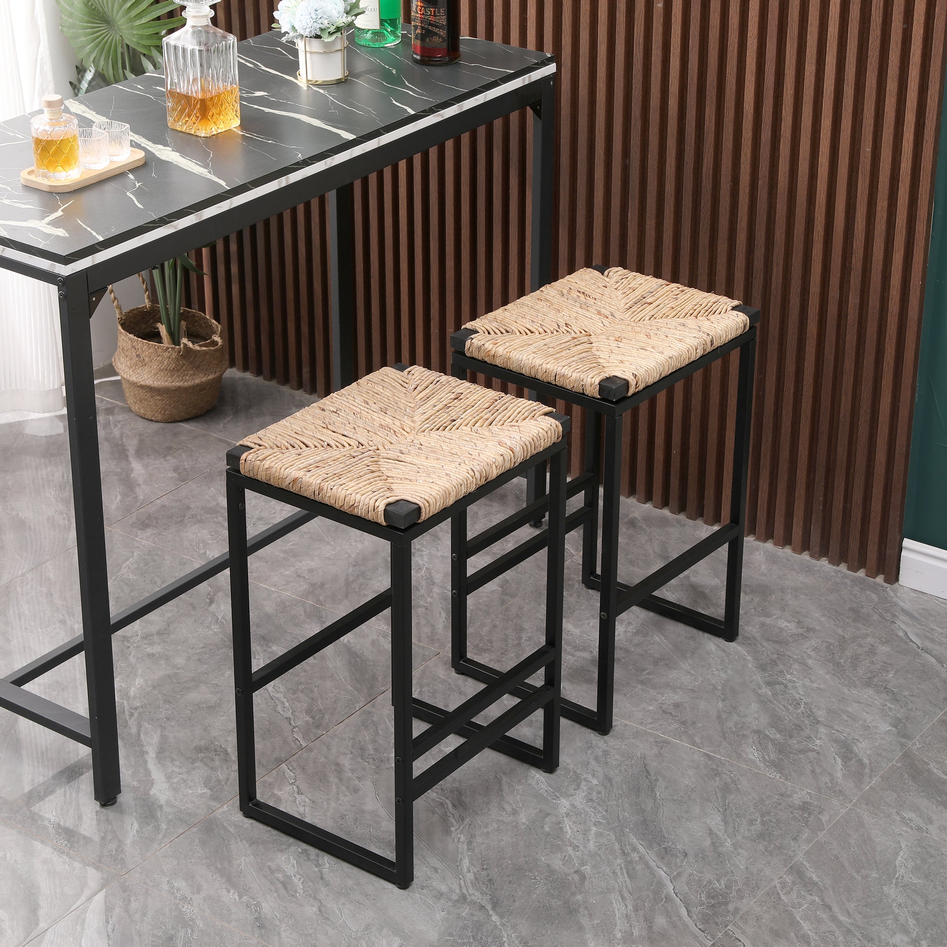 Two woven rattan bar stools with black metal frames near a high table