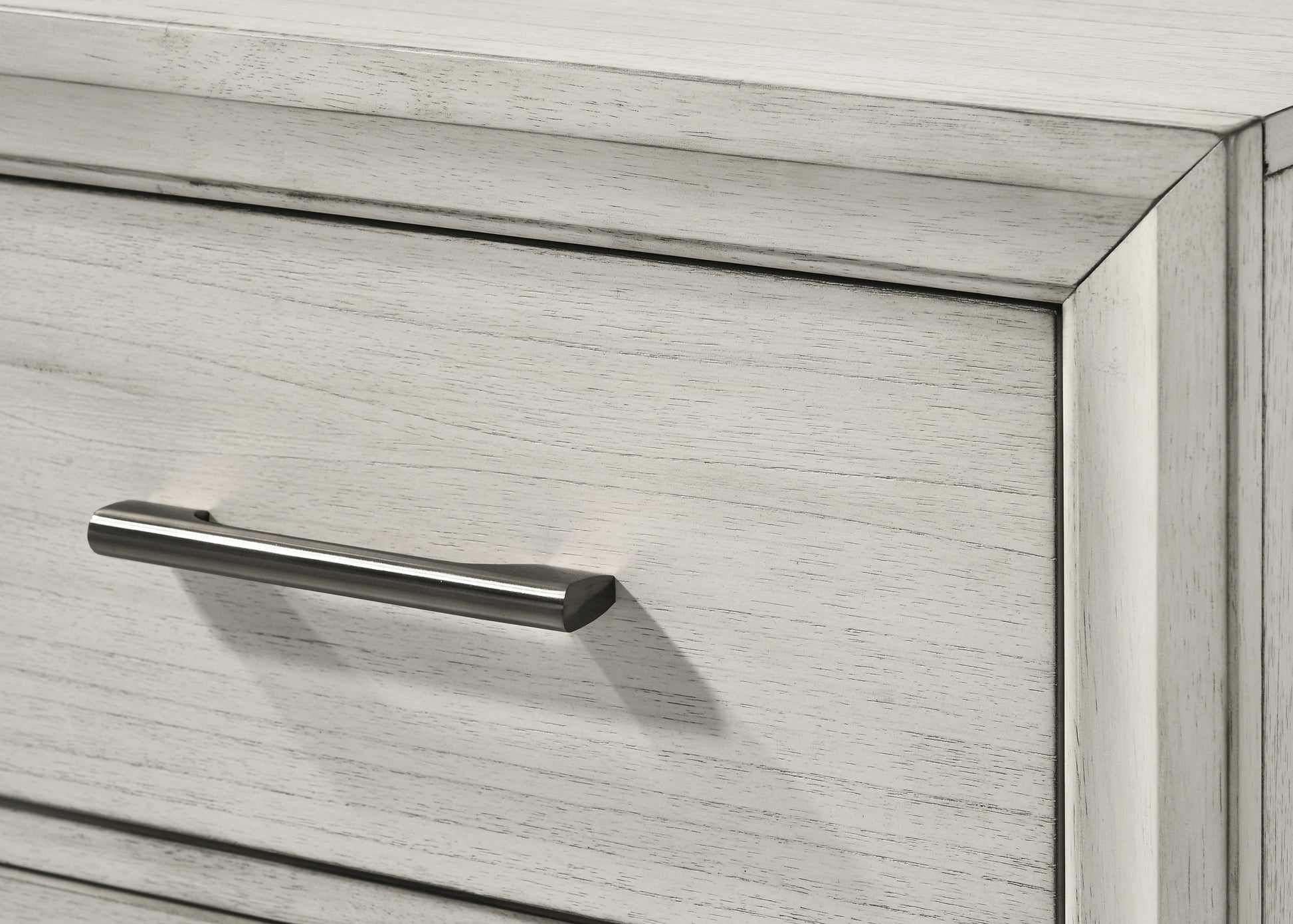 Closeup of a light gray distressed wood dresser drawer with a brushed nickel handle