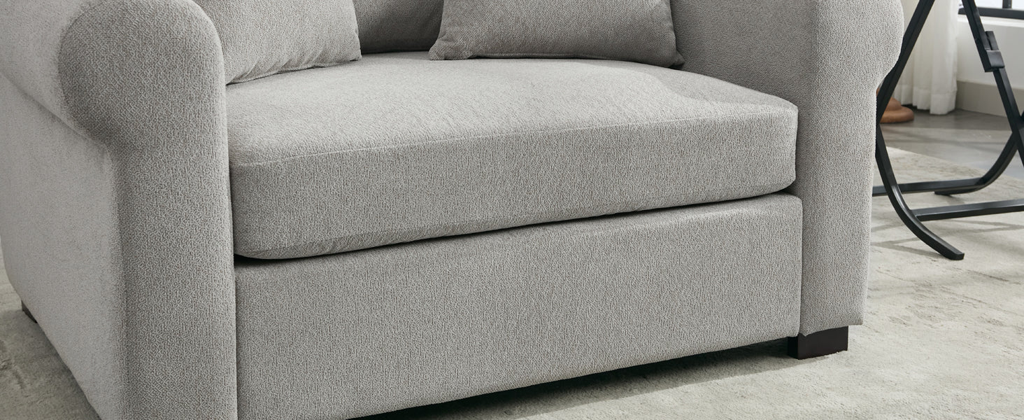 Closeup of a plush grey armchair with textured fabric and rolled arms