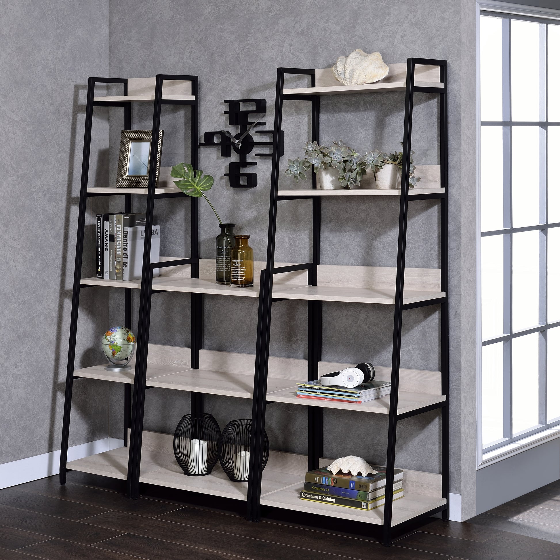 Black metal and light wood ladder bookshelf with framed art and plants
