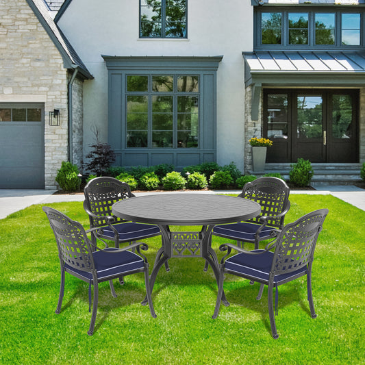 Dark grey cast aluminum patio dining set with intricate scrollwork chairs and a patterned tabletop
