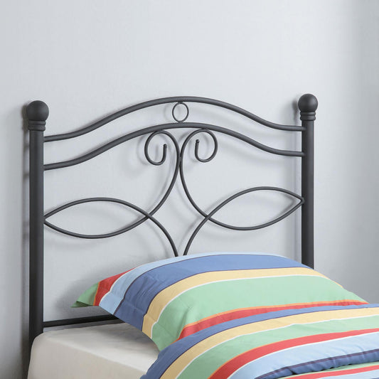 Black metal headboard with ornate scrollwork and finials complementing a striped pillow