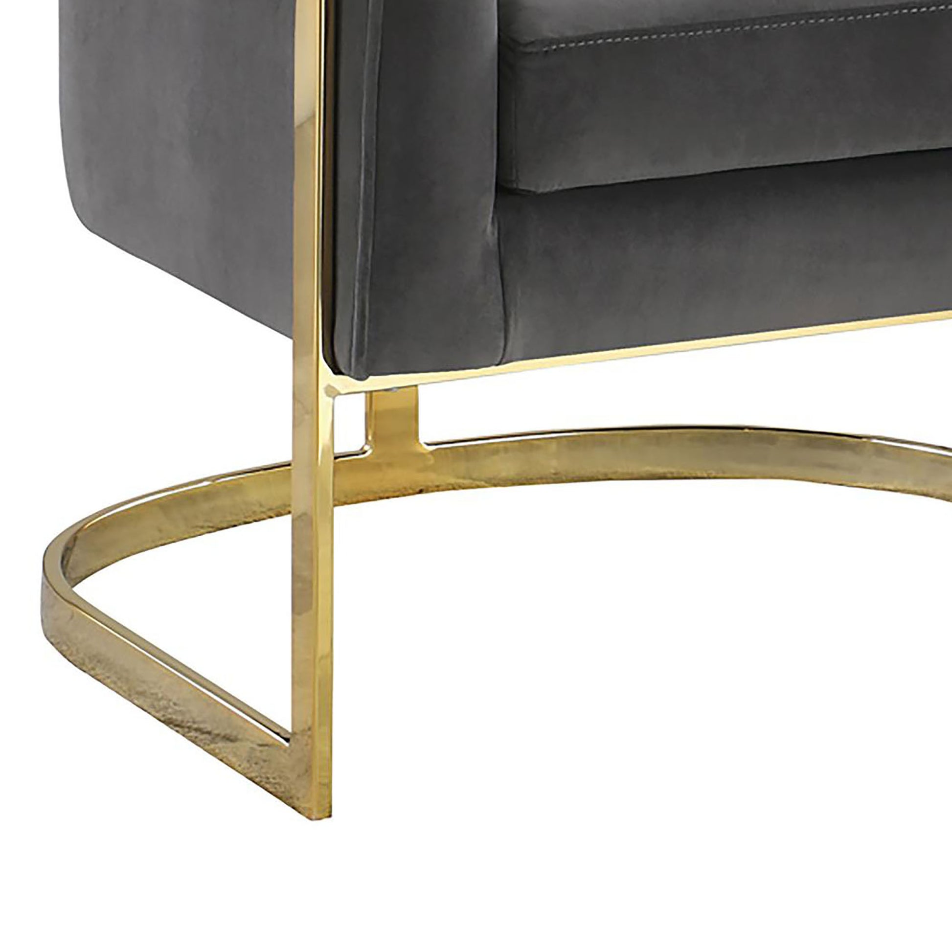 Closeup of a dark gray velvet armchair with polished brass legs showcasing tufted details and modern design